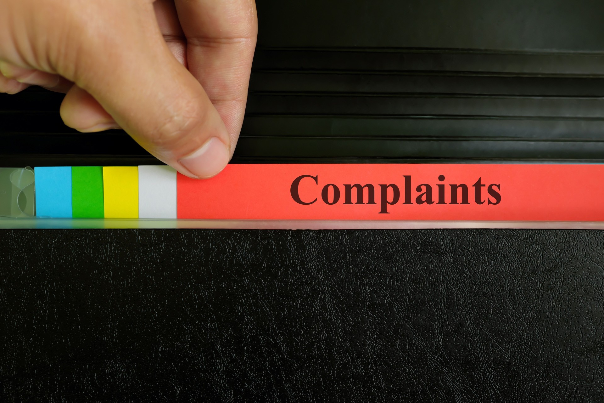 Hand picking complaints file record in black binder folder. Customer complaint business and crime concept.